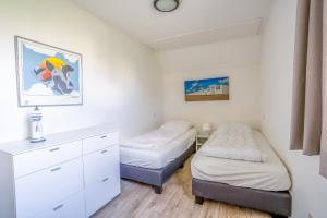 Un dormitorio con dos camas y una cómoda. en Villapark Kamperfoelie 91, en De Koog 8 fotos más