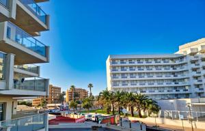 a view of a hotel with palm trees and buildings at Cozy apartment with a fantastic sea view in Cala Millor