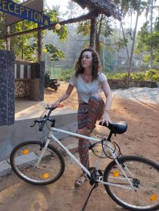 a woman is standing next to a bike at Molly's Hostel in Varkala
