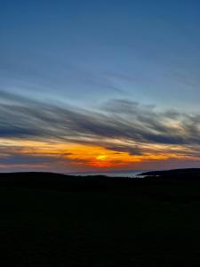 a sunset over a field with the sky at Kirkbride farm holiday cottages 