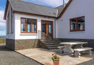 a white house with a picnic table and a bench at Kirkbride farm holiday cottages 