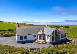 a large white house with a porch on a field at Kirkbride farm holiday cottages 