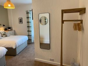 1 dormitorio con espejo junto a la cama en Glenthorne Guest House, en Tenby