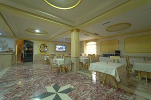 - un restaurant avec des tables et des chaises dans une salle dans l'établissement Olimpic Hotel, à Tirana