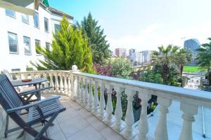 balcón con barandilla blanca, mesa y silla en Olimpic Hotel en Tirana
