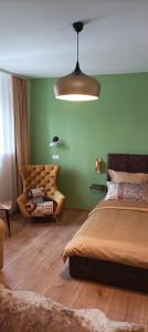 Guest House Klaudija في تروغير: غرفة نوم بجدران خضراء وسرير واريكة