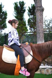 a little girl riding on the back of a horse at Pamukkale Apollon Garden in Denizli