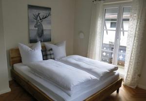 a bedroom with a bed with white sheets and a window at Alpenhof Garnihotel & Ferienwohnungen in Garmisch-Partenkirchen