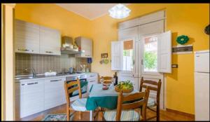 a kitchen with a table and chairs and yellow walls at 2 bedrooms apartement at Avola 150 m away from the beach with sea view enclosed garden and wifi in Avola