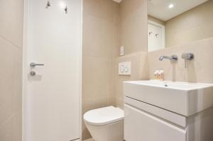 a bathroom with a white toilet and a sink at Regents Serviced Apartments by StayPrime in London