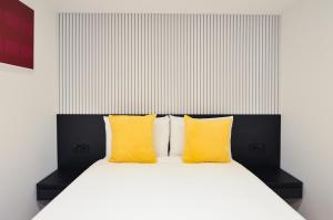 a bed with two yellow pillows on top of it at Regents Serviced Apartments by StayPrime in London