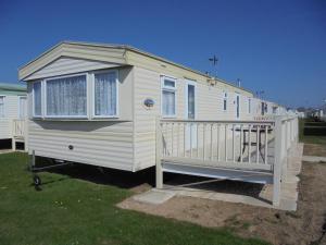 a white tiny house with a porch on the grass at 6 Berth The Chase Ingoldmells (Abi II) in Ingoldmells