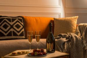 uma garrafa de champanhe e dois copos num sofá em My Opéra em Paris