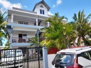 een wit huis met palmbomen ervoor bij 2 bedrooms apartement with furnished terrace and wifi at Trou aux Biches 1 km away from the beach in Trou aux Biches