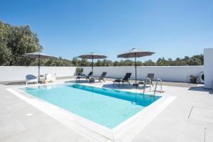 a swimming pool with chairs and umbrellas on a building at VillaPhysis with Private Pool in Lardos