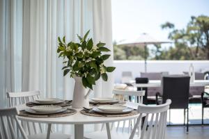 a white table with plates and a vase of flowers at VillaPhysis with Private Pool in Lardos