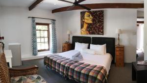 a bedroom with a bed and a painting on the wall at Old Potters Inn in Greyton