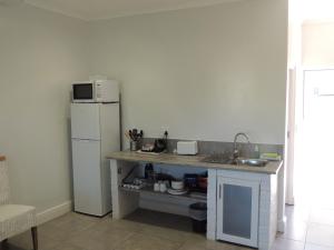 a small kitchen with a white refrigerator and a counter at Sand Dollar @ The Dunes in Plettenberg Bay