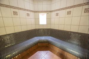 a tiled bathroom with a tub with a window at Spa Hotel Bily Horec in Harrachov