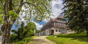 a large house on a hill with a dirt road at Spa Hotel Bily Horec in Harrachov