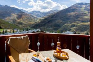 una mesa en un balcón con vistas a las montañas en Résidence Pierre & Vacances Premium Les Alpages de Reberty, en Les Menuires