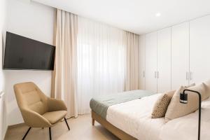 a bedroom with a bed and a chair and a television at Central Suites in Santa Cruz de Tenerife