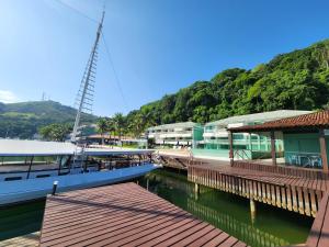 a boat docked at a dock with a building at AP ALECRIM Luxo Cond Aquarius I Angra dos Reis in Angra dos Reis