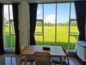 日惹Giori Rice Field View Syariah的一间有桌子、椅子和大窗户的房间