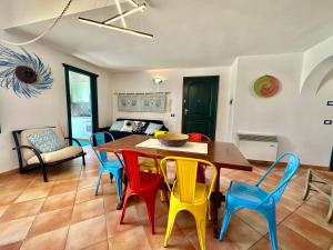 a dining room with a table and colorful chairs at Jennas-Grecale Apartment in Àrbatax