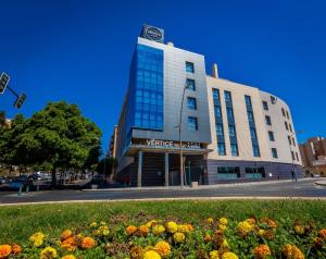 a building on a street with flowers in front of it at Vértice Indalo Almería in Almería