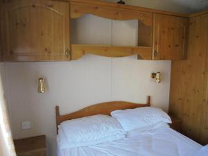 a bedroom with a bed with a wooden headboard at 6 Berth on Golden Sands (Celebration) in Ingoldmells