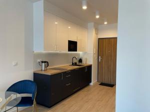 una cocina con armarios negros y una silla azul en Apartament przy Marsa, en Varsovia