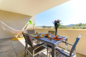 ein Esszimmer mit einem Tisch und Stühlen sowie einem Balkon in der Unterkunft SELECT SO HOME - Magnifique appartement dans une résidence avec piscine et à proximité des plages - POS35 in Bormes-les-Mimosas