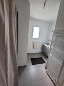 ein weißes Bad mit einem Waschbecken und einem Fenster in der Unterkunft Maison de ville neuve in Les Essarts