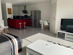 ein Wohnzimmer mit einem TV und eine Küche mit roten Schränken in der Unterkunft Maison de ville neuve in Les Essarts