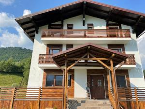 a house with a wooden fence in front of it at Pensiunea ACASA LA VLADUȚ in Borşa
