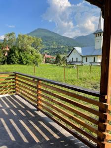 a wooden fence in front of a church with a field at Pensiunea ACASA LA VLADUȚ in Borşa