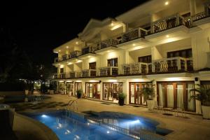 a building with a swimming pool in front of it at night at White Pearl Suites by Rosetum in Old Goa
