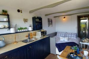 uma cozinha com um lavatório e uma cama num quarto em The Cloves Farm Shepherd’s Hut em Lydford