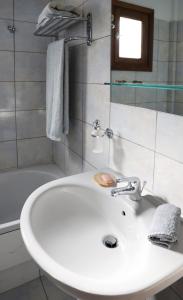 bagno con lavandino bianco e vasca di Condo in Aegina a Città di Egina