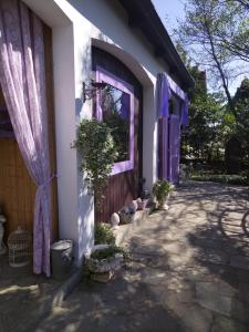 a white house with purple doors and potted plants at Cuore Verde in Cavour