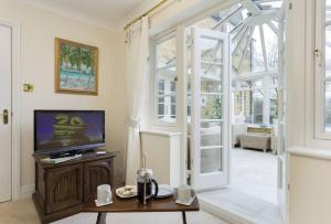 a living room with a television and a living room with a window at Chipping Campden - Cotswolds private house with garden in Chipping Campden