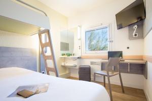 a bedroom with a bed and a desk with a computer at Ibis Budget Fréjus Capitou in Fréjus