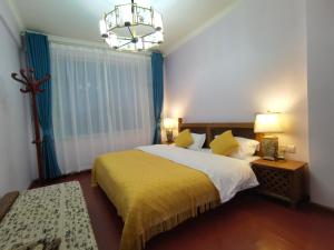 a bedroom with a bed with a yellow blanket and a chandelier at Mama Naxi Guesthouse in Lijiang