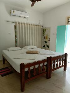um quarto com uma cama grande e lençóis brancos em Molly's Hostel em Varkala