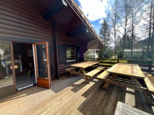drewniany taras z dwoma stołami piknikowymi w obiekcie Chalet les Bleuets 12p - babyfoot & Wii w mieście Gérardmer