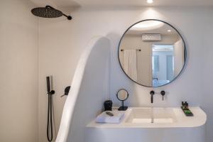 een witte badkamer met een wastafel en een spiegel bij Akra Suites & Spa in Imerovígli