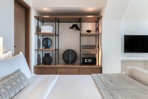 um quarto com uma cama branca e uma televisão em Akra Suites & Spa em Imerovigli