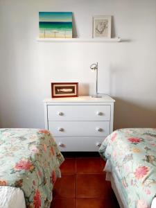 a bedroom with two beds and a dresser with a picture at Charme Apartment Center in Angra do Heroísmo