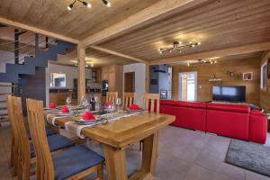 une salle à manger avec une table en bois et un canapé rouge dans l'établissement Chalet La Trinité-Spa,Sauna,Pétanque-Gérardmer, à Gérardmer